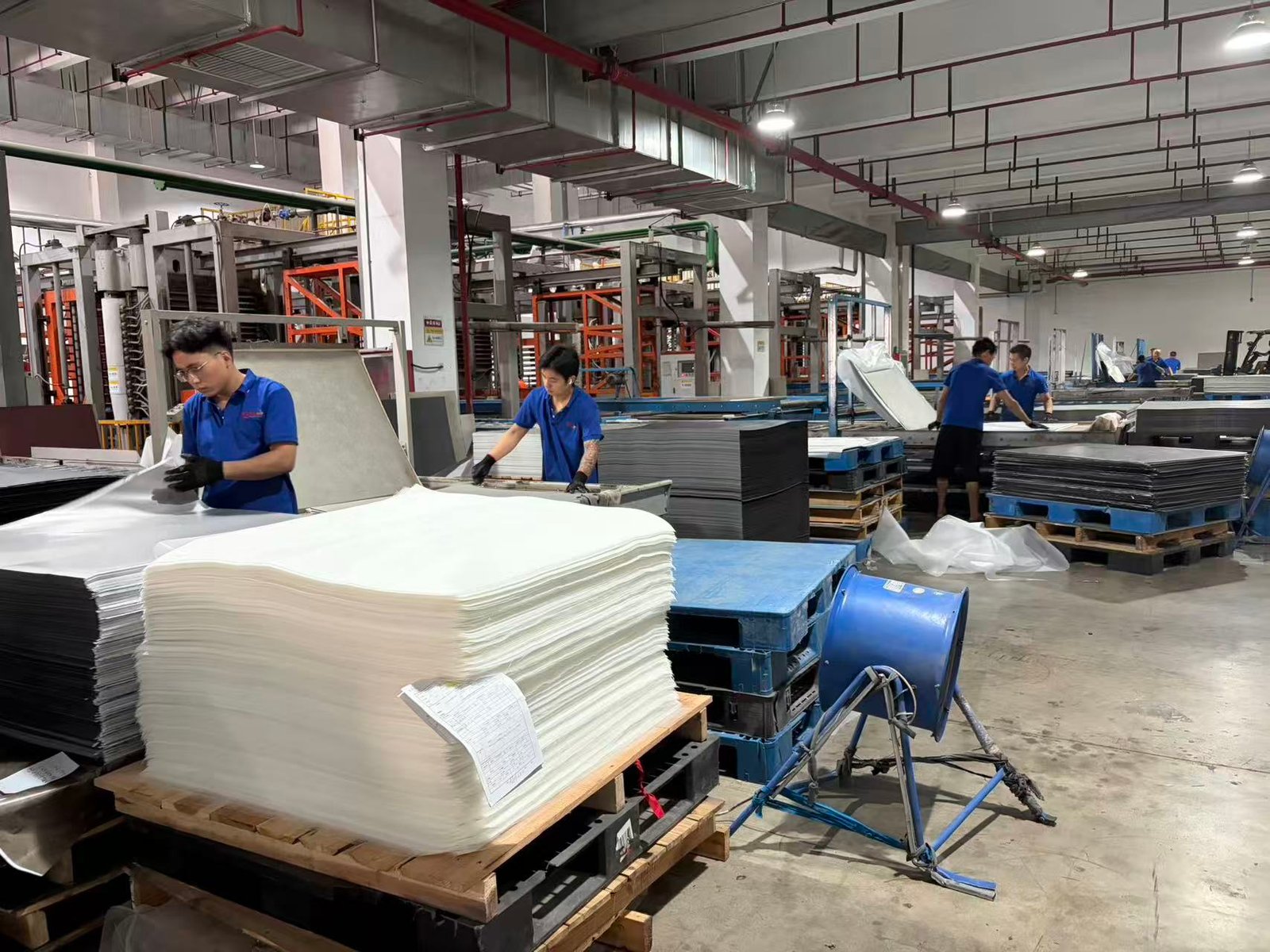 Operators working beside the LVT hot-press production line at the Ecoflors production base
