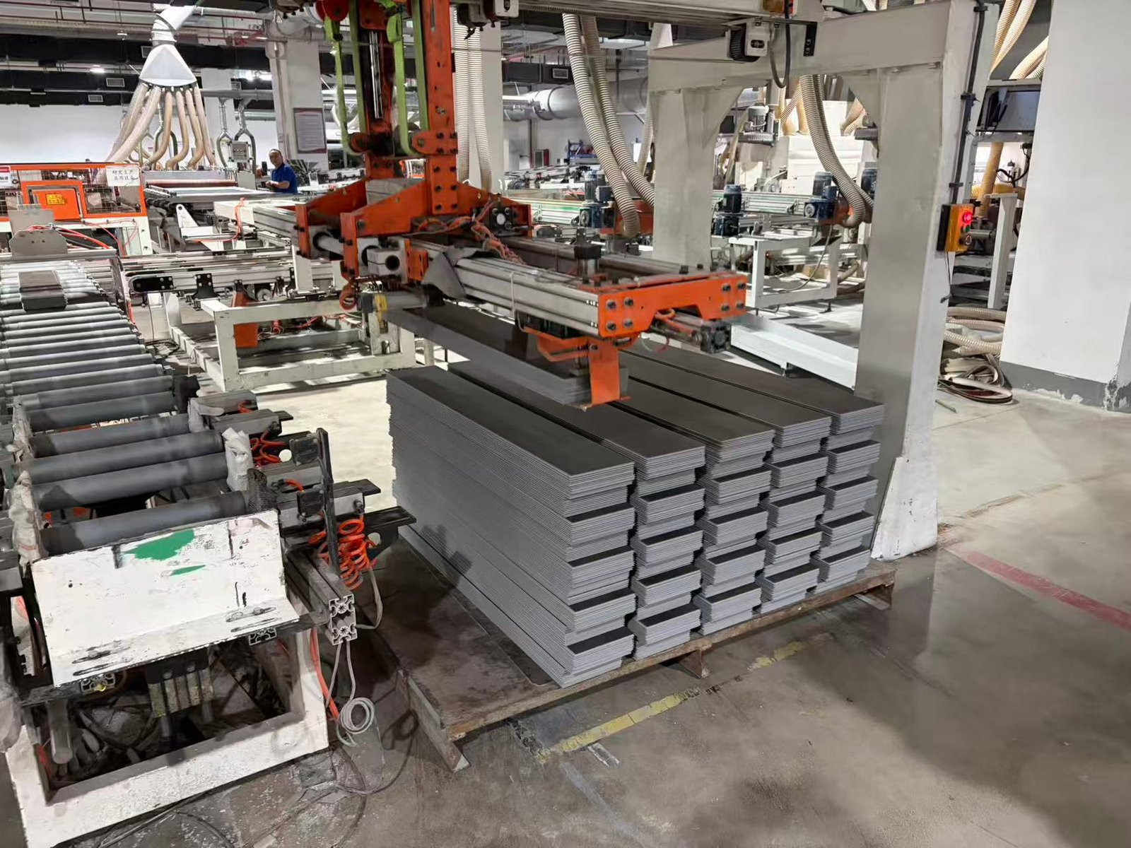 SPC flooring planks stacked beside the click-profile slotting line