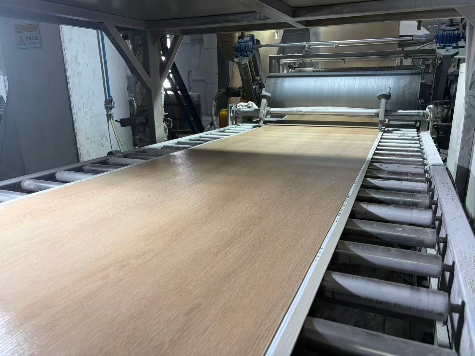Wood-look SPC flooring board leaving the extrusion line at the Ecoflors production base
