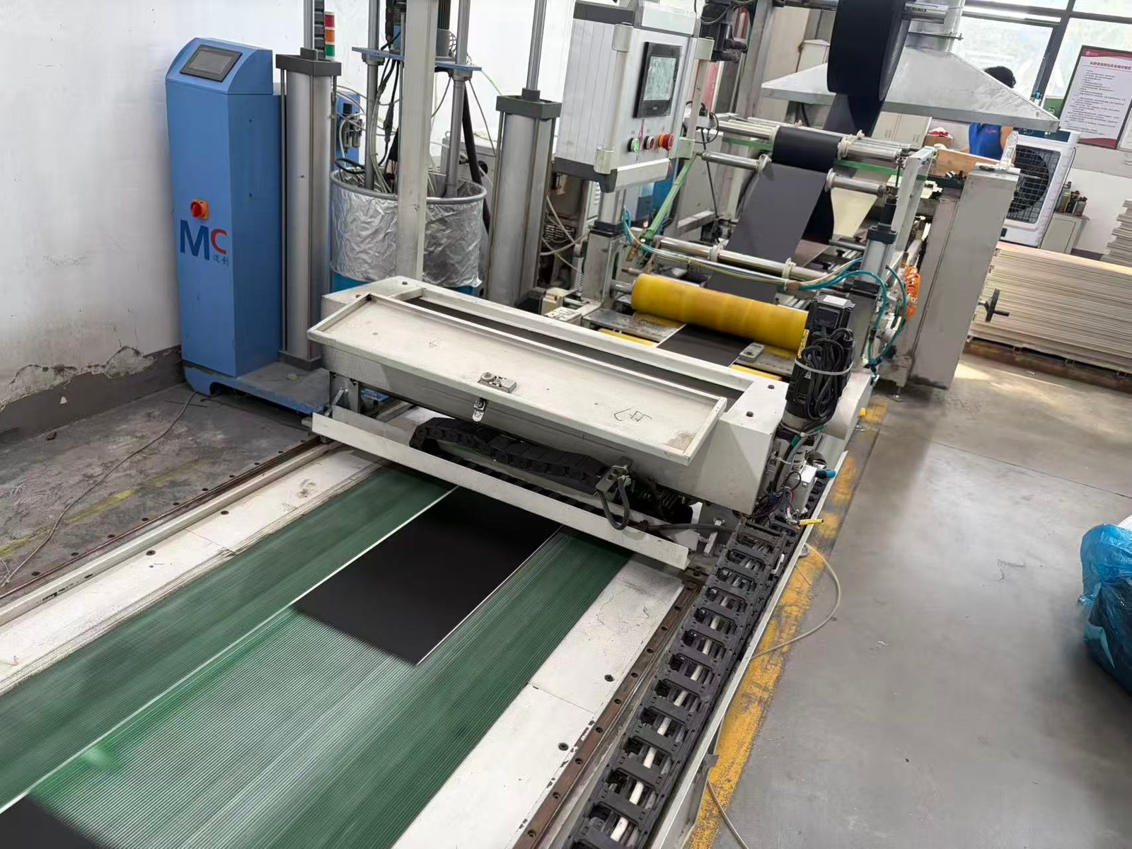 Flooring boards receiving a pre-attached backing layer on the lamination line